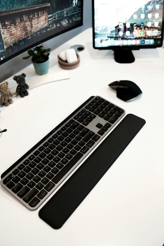 a keyboard sitting on a desk with two monitors