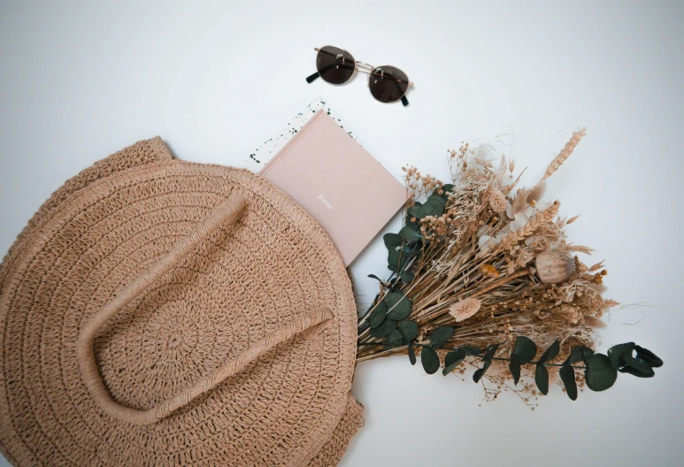 there is a straw hat with sunglasses, books and plants