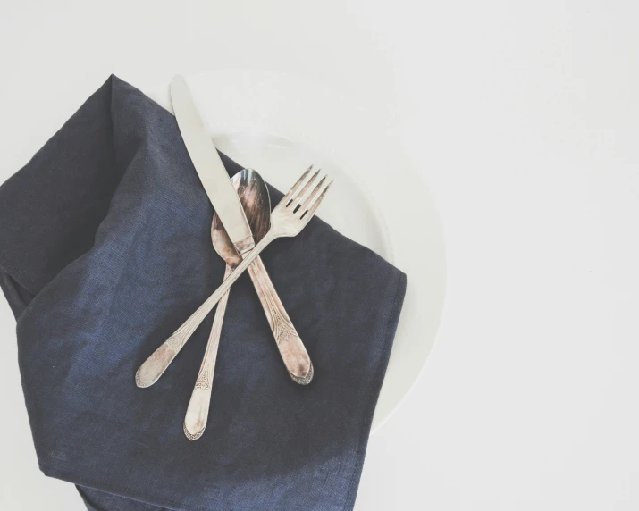 fork and knife sitting on a napkin with some silverware on top