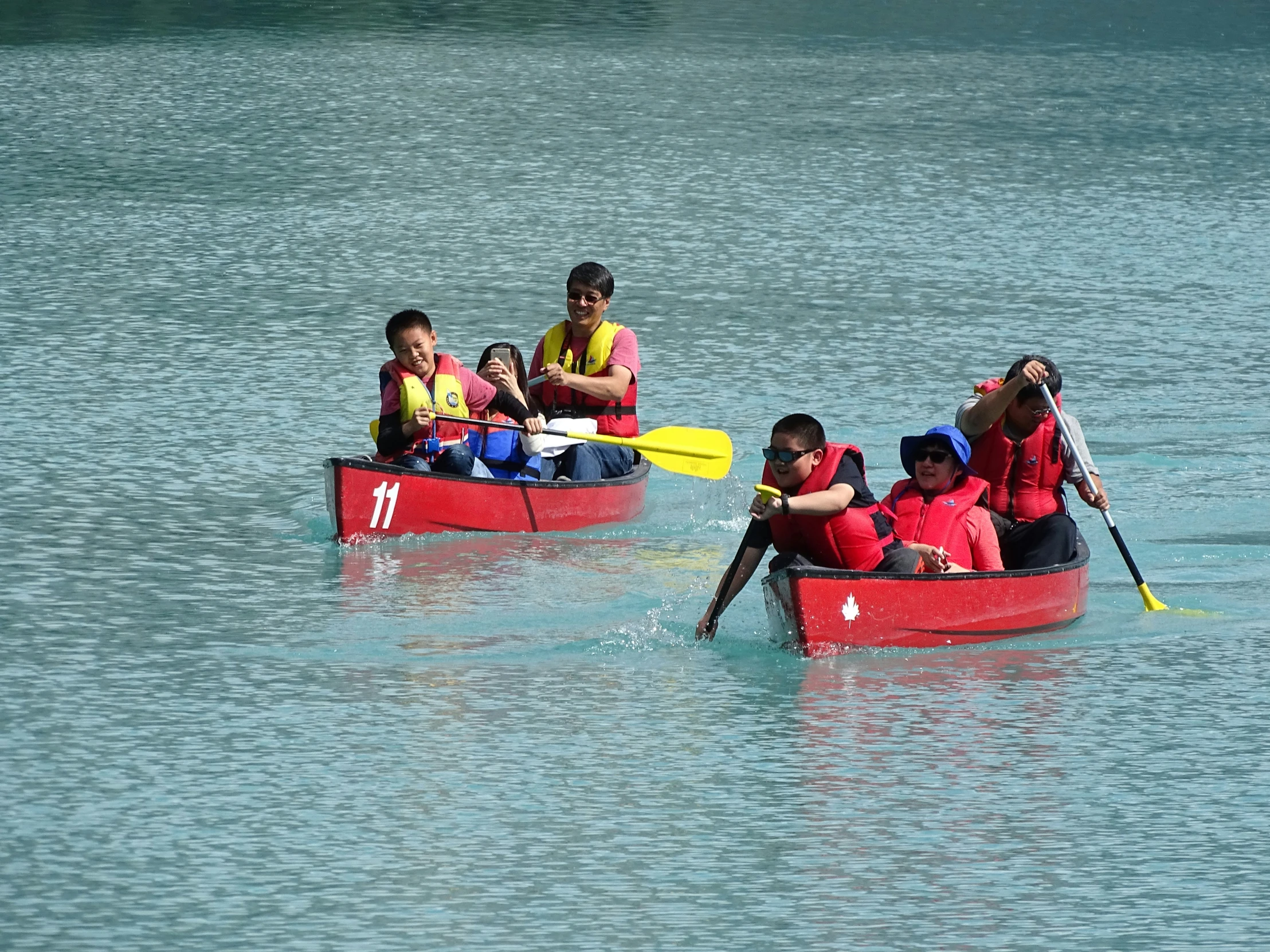 four people in a boat in the water with paddles