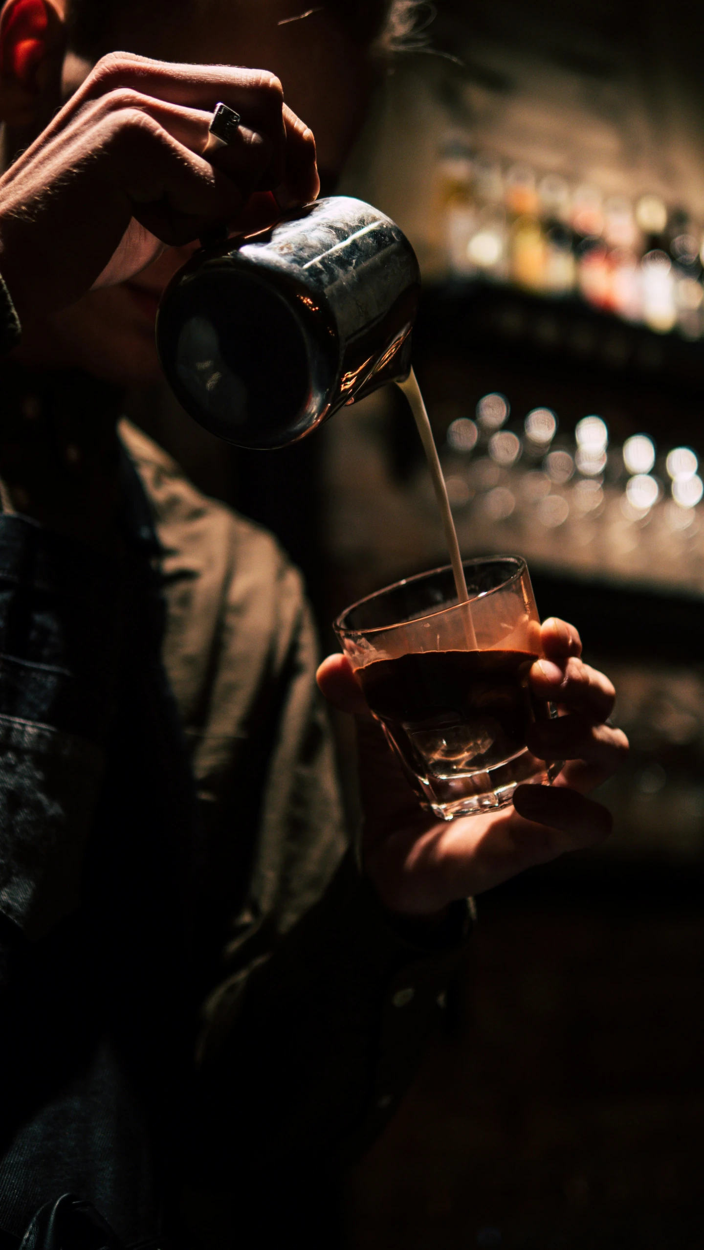 a person is holding a glass and pouring drink