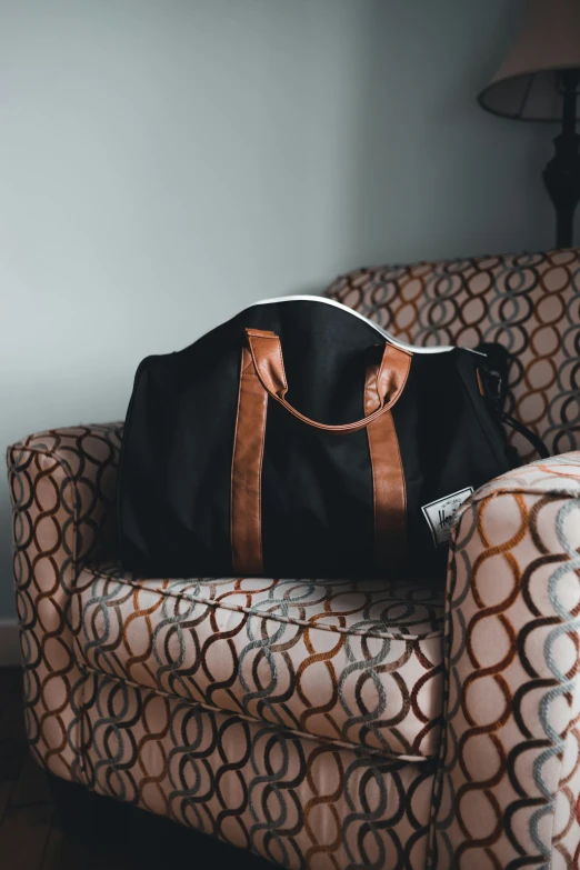 an orange, brown and white chair with a large black bag