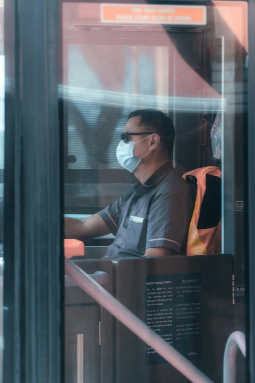 a man sitting inside of a bus wearing a face mask