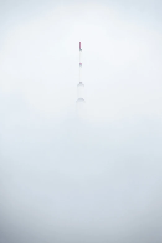 the clock tower towers in a thick foggy sky