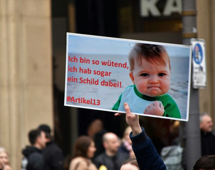 a baby is holding up a sign at a demonstration