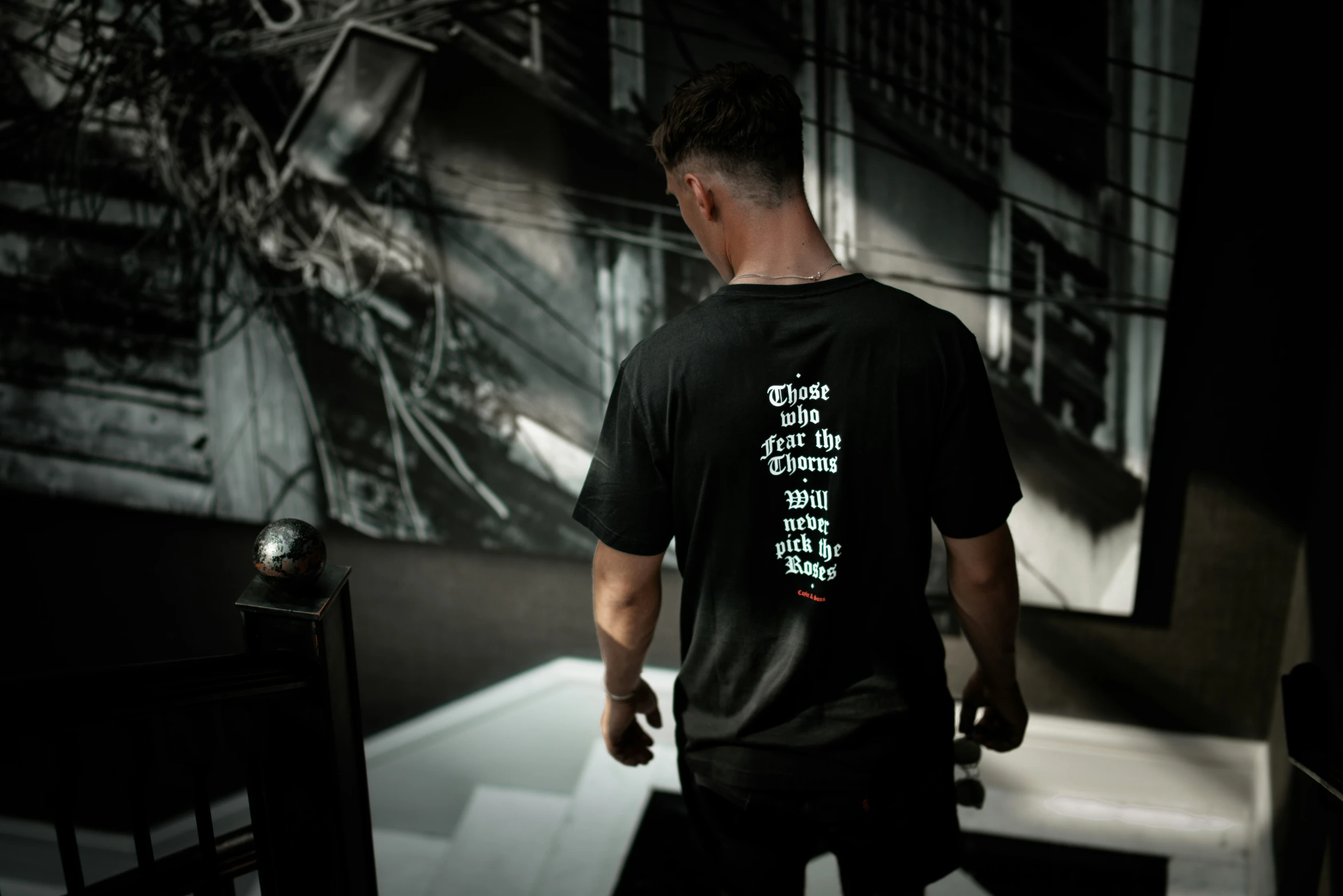 a person wearing a black shirt and black pants with an iron clock on the wall