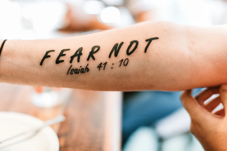 a tattoo saying fear not on someone's arm