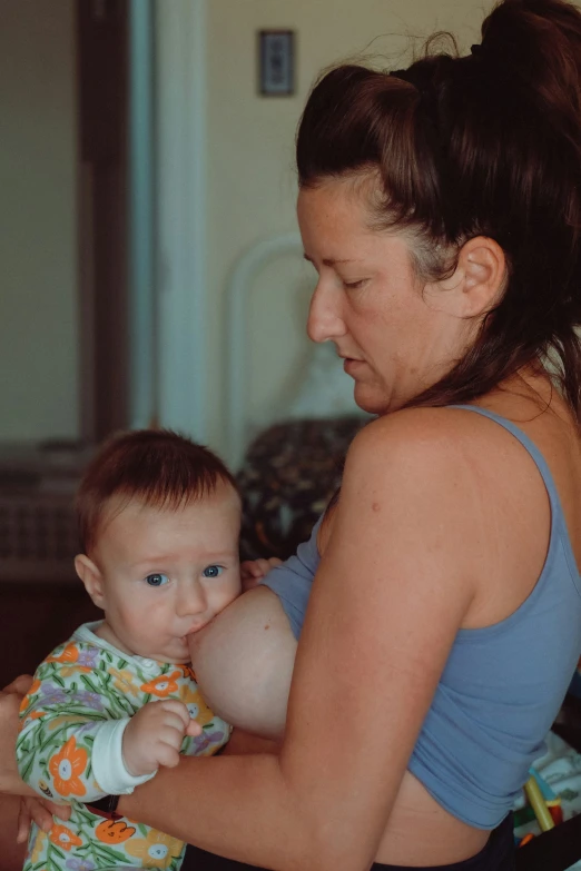 a woman in blue tank top holding a small baby