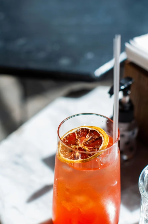 a glass with  orange and a straw on a table