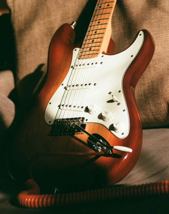 a guitar sitting on a couch next to a phone