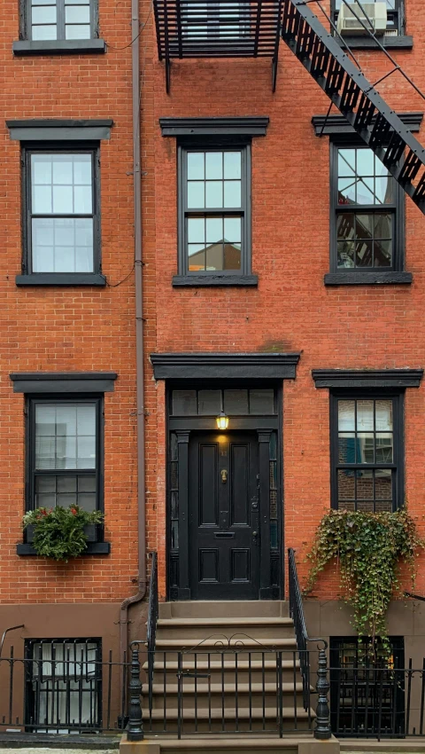 a brick town house with black front door and staircase