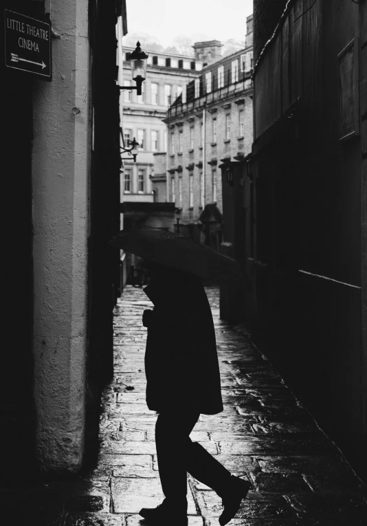 black and white pograph of man holding an umbrella in the rain