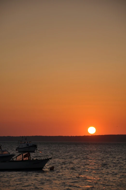 a large boat in the water as the sun sets