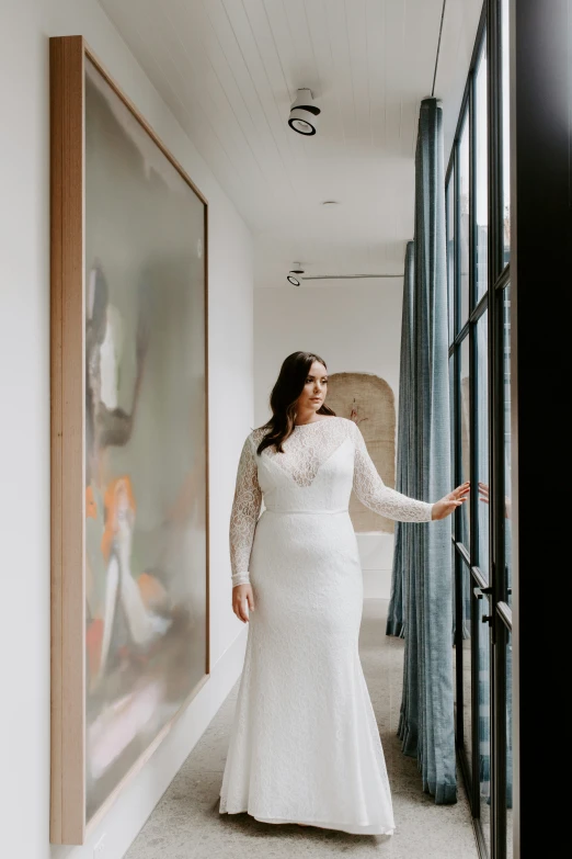 a woman in a white dress is standing next to a glass