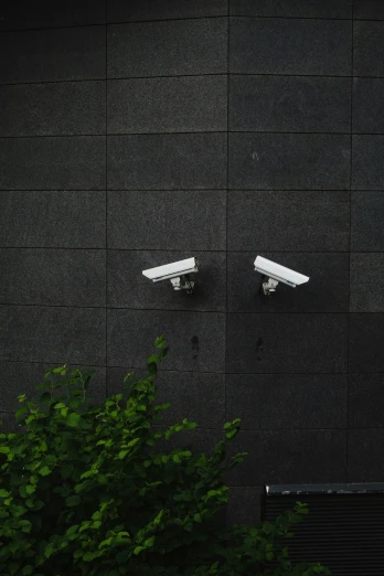 two bullet cameras in front of a black wall
