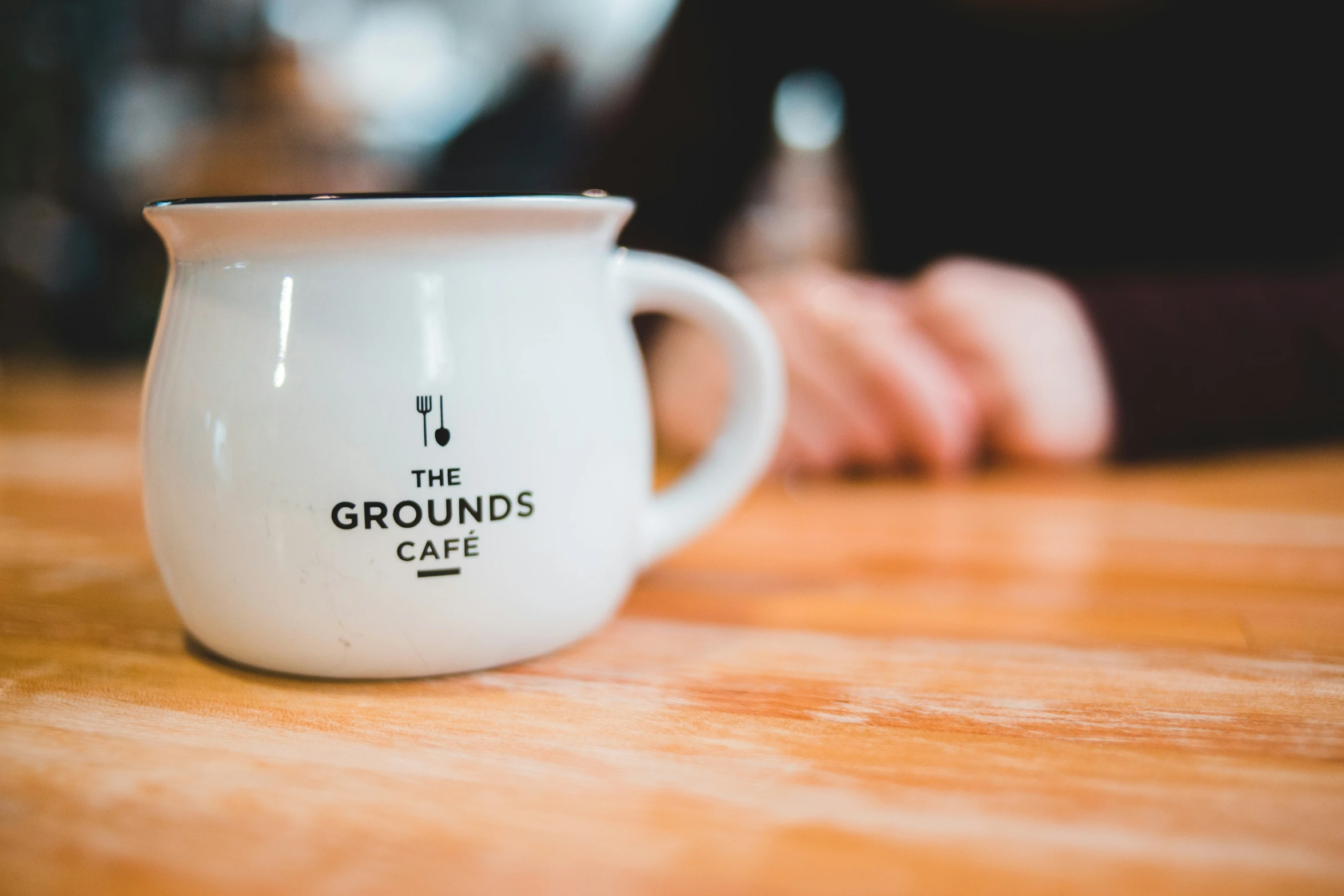 a mug with the grounds cafe logo is shown