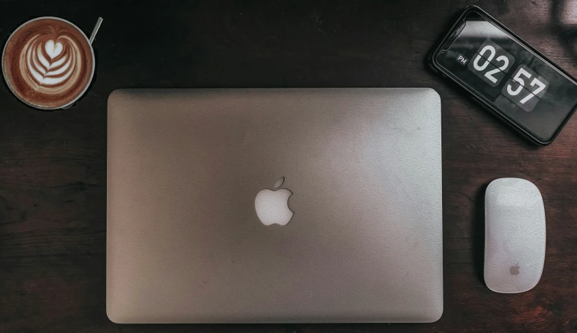 the computer, mouse and wallet are setting on a wooden desk