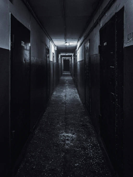 long dark hallway with doors on both sides and multiple lockers