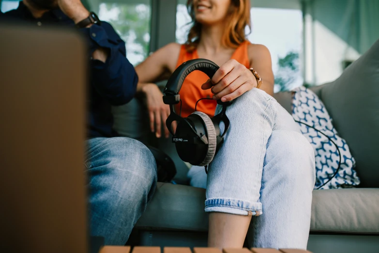 a woman sitting on top of a couch holding onto a pair of headphones