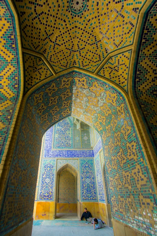 a person in blue and yellow is sitting under an archway