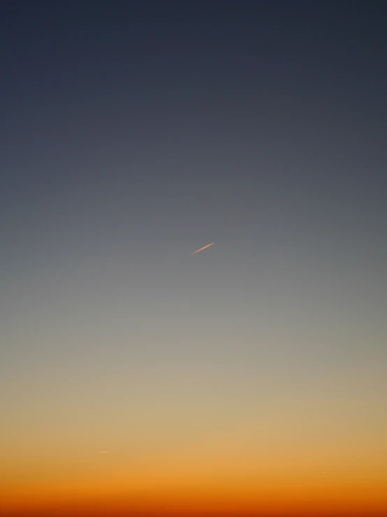 an airplane flies overhead during sunset in the sky