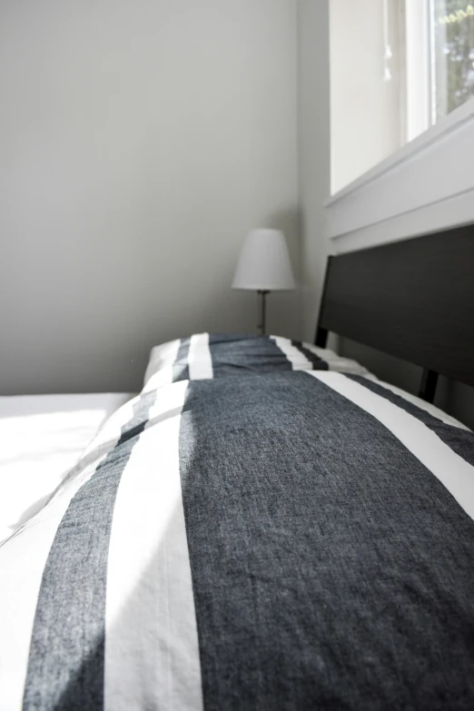 a bed with white and gray sheets on top of it