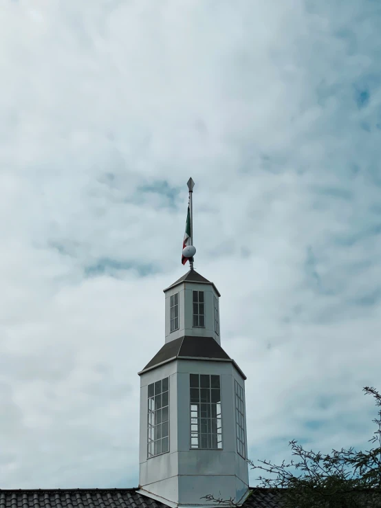 a white building with a steeple under a cloudy sky