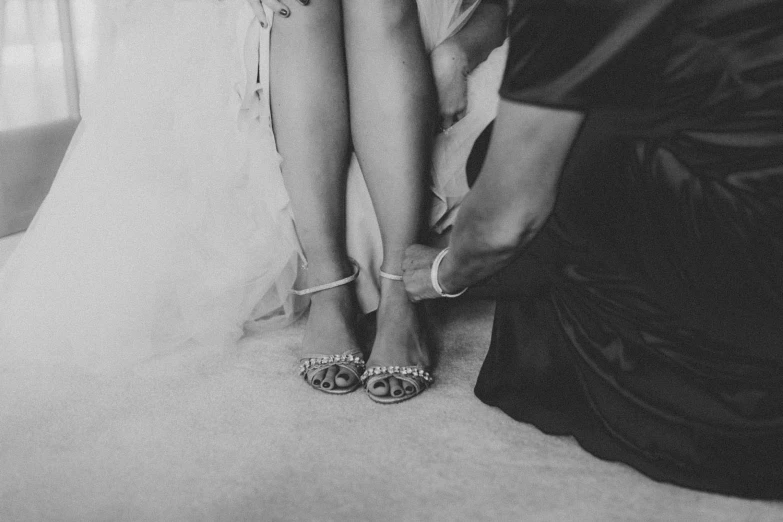 two women wearing wedding shoes by a window