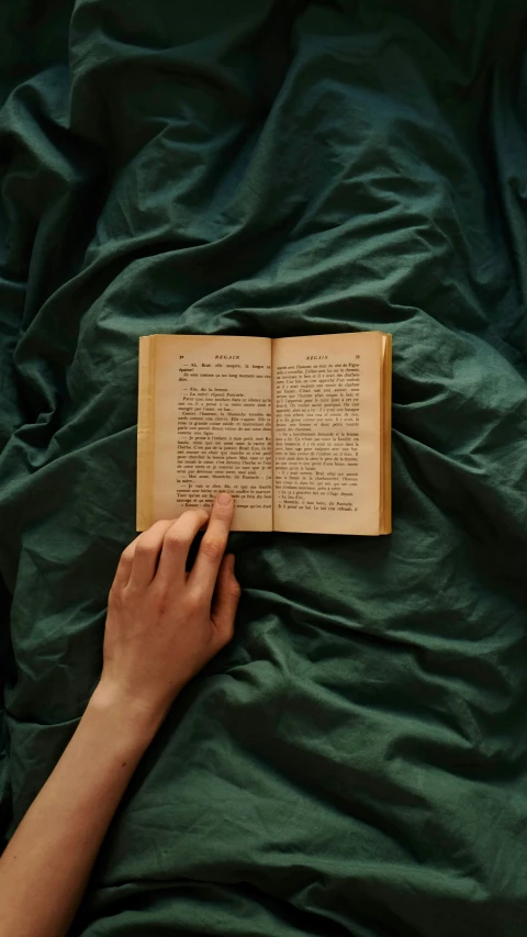 someone laying on a bed while reading a book