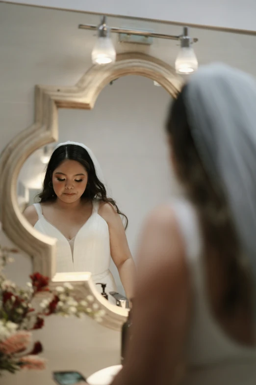 the bride is looking at her hair and putting on lipstick