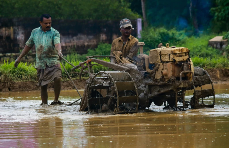 two men working in muddy waters next to a road