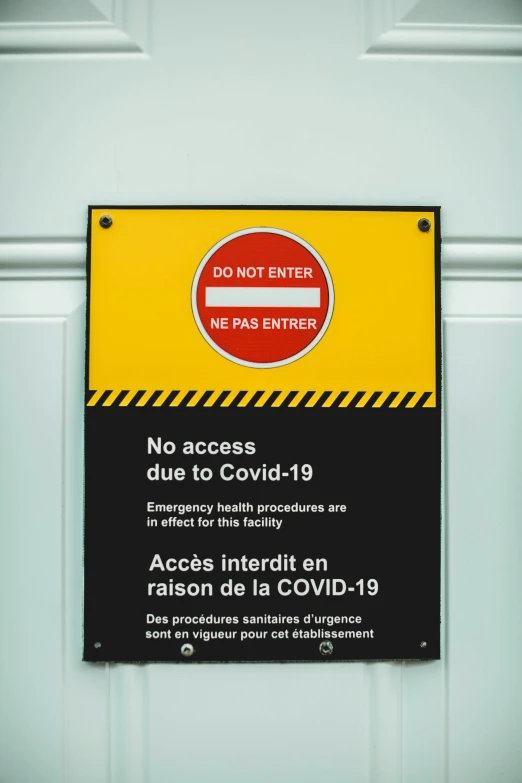 a black and yellow caution sign hanging on a white door