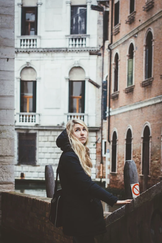 young woman standing on ledge of street in city