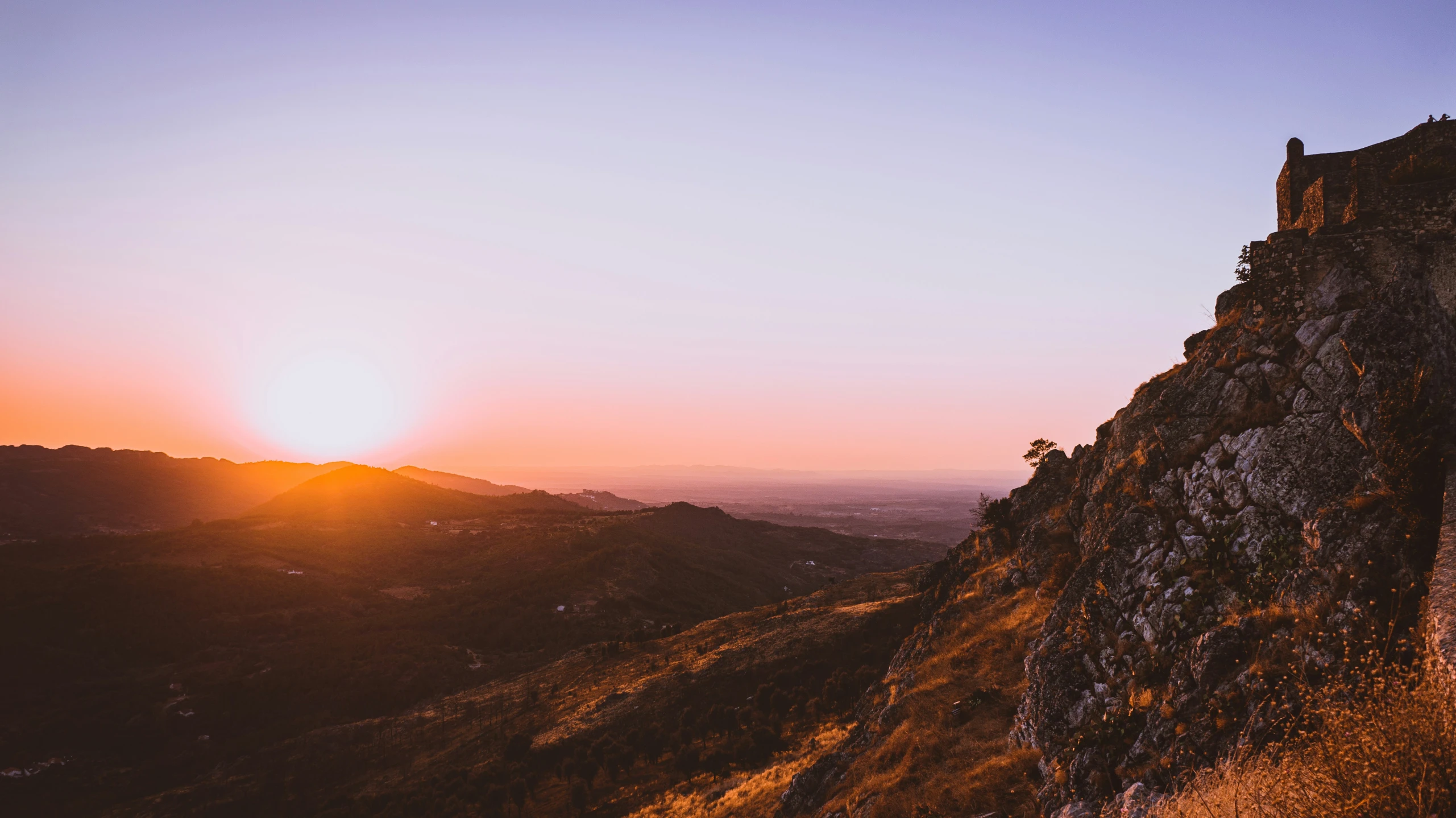 the sun is setting over a steep hill on the side of the mountain