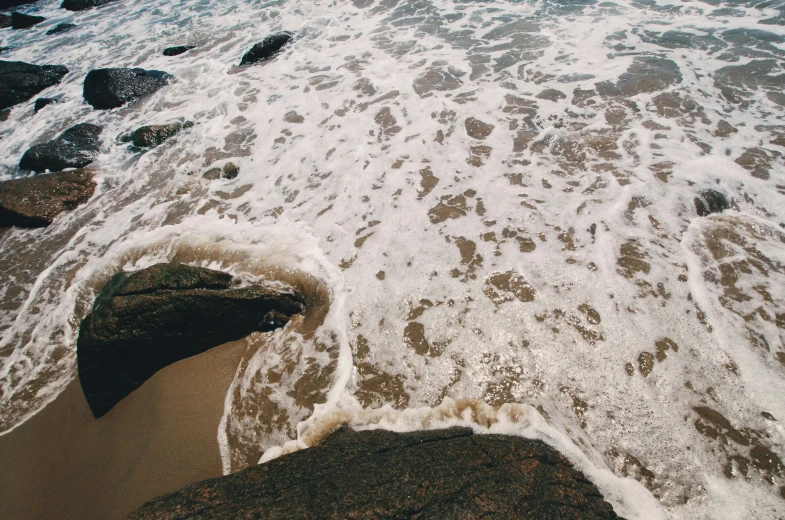 the view from above shows a tide crashing on a beach