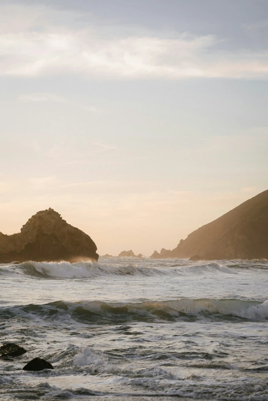 waves crashing on the shore, while the sky is partially cloudless