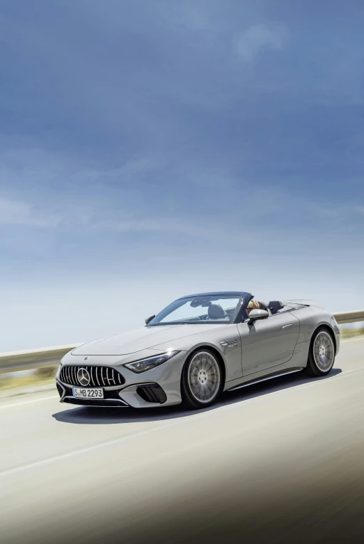 a silver mercedes benz roadster convertible driving on the road