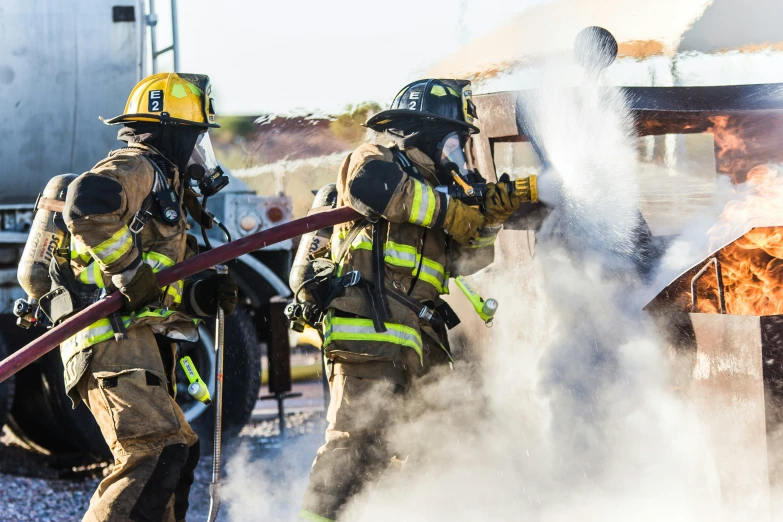 two firefighters are spraying water on the flames