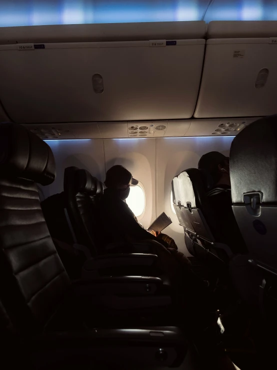 people sitting inside an airplane looking at their phones