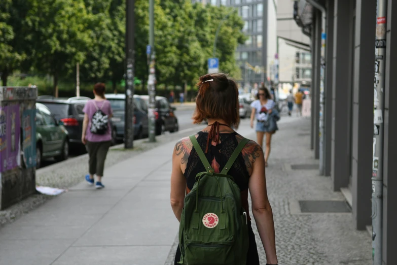 a woman walking down the street carrying an oversize backpack