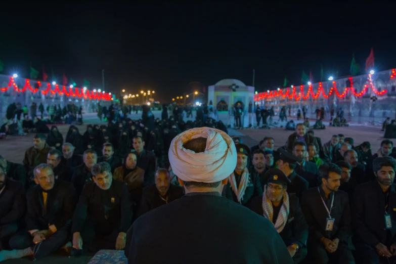 an event is being attended in the dark with people sitting outside and people walking about