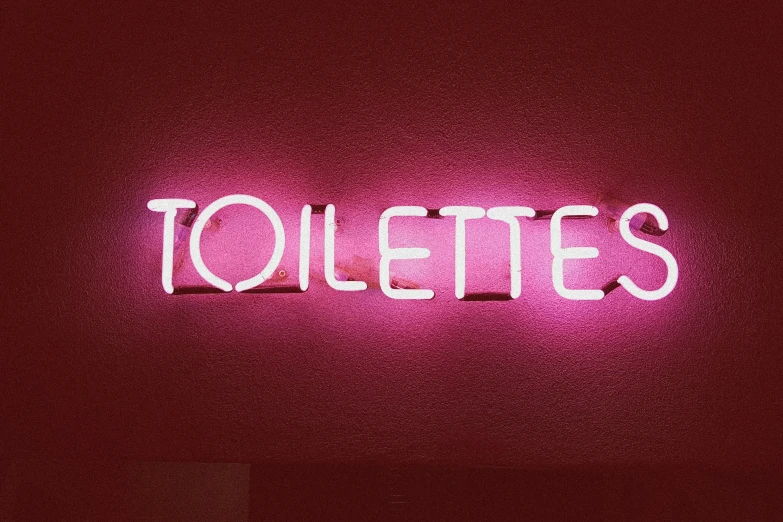 lighted sign that reads toilets on a wall