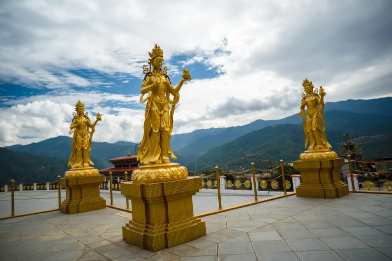 some golden statues are standing on a stone surface