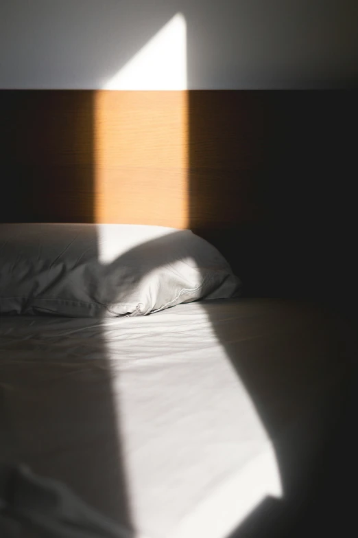 a white bed with white sheets and brown headboard