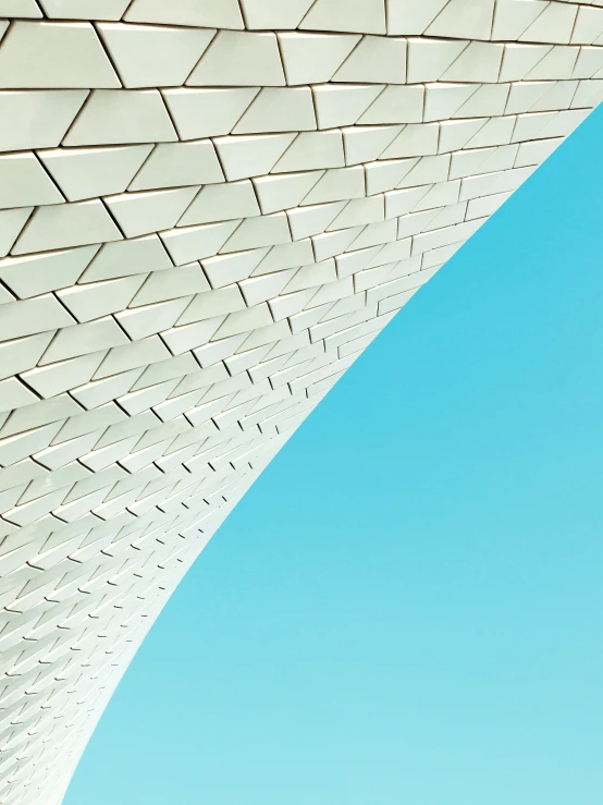 the underside of a curved white building, with blue sky above