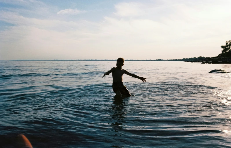 a woman standing in the water next to a boat