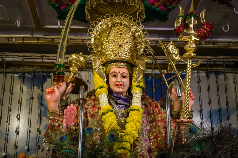 a large statue with elaborate gold paint, standing behind a pole