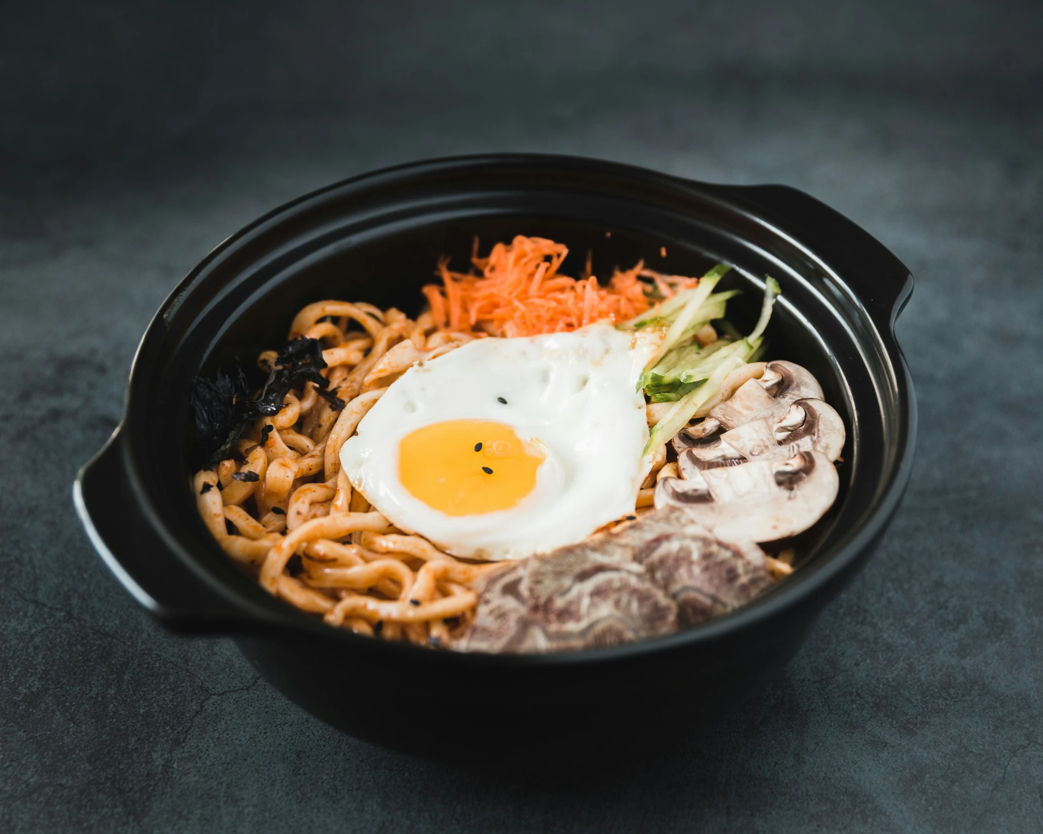 a bowl filled with food, noodles and an egg