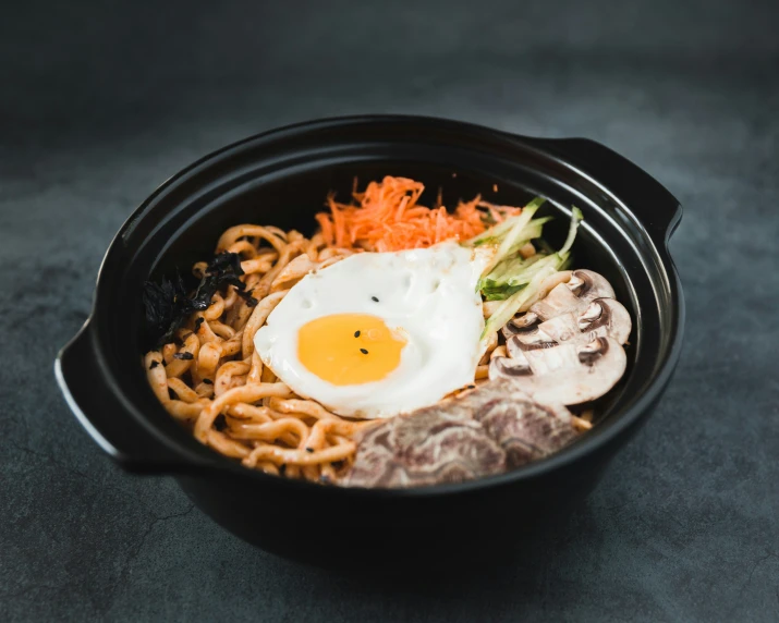 a bowl filled with food, noodles and an egg