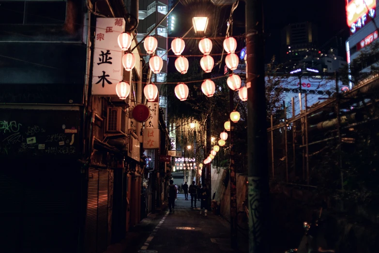 a dimly lit asian street is adorned with paper lanterns